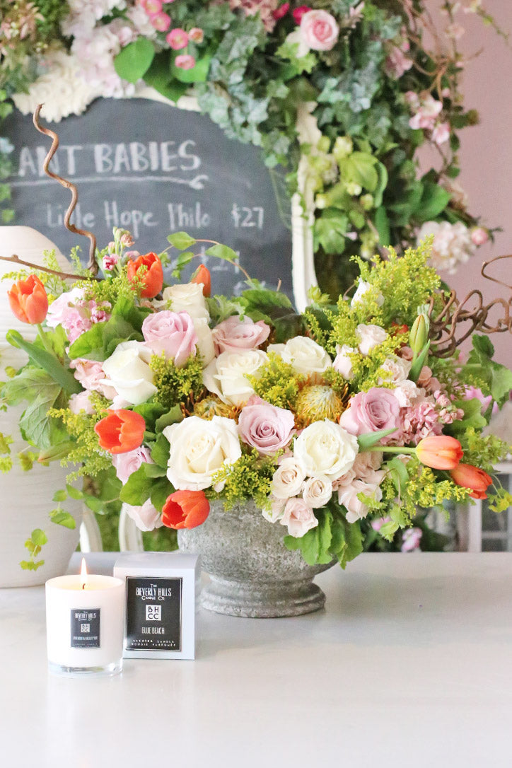 Blush and melon roses, tulips and protea framed by sculptural kiwi branches