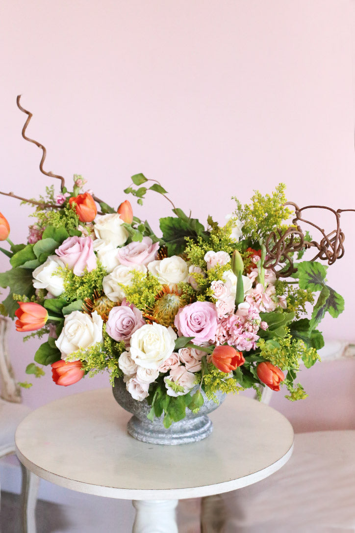 Blush and melon roses, tulips and protea framed by sculptural kiwi branches