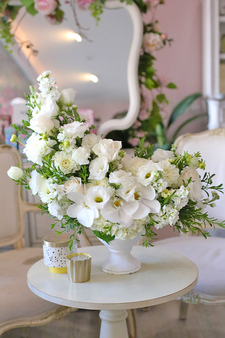 White roses, orchids and lisianthus with dahlias in a stylish white vase