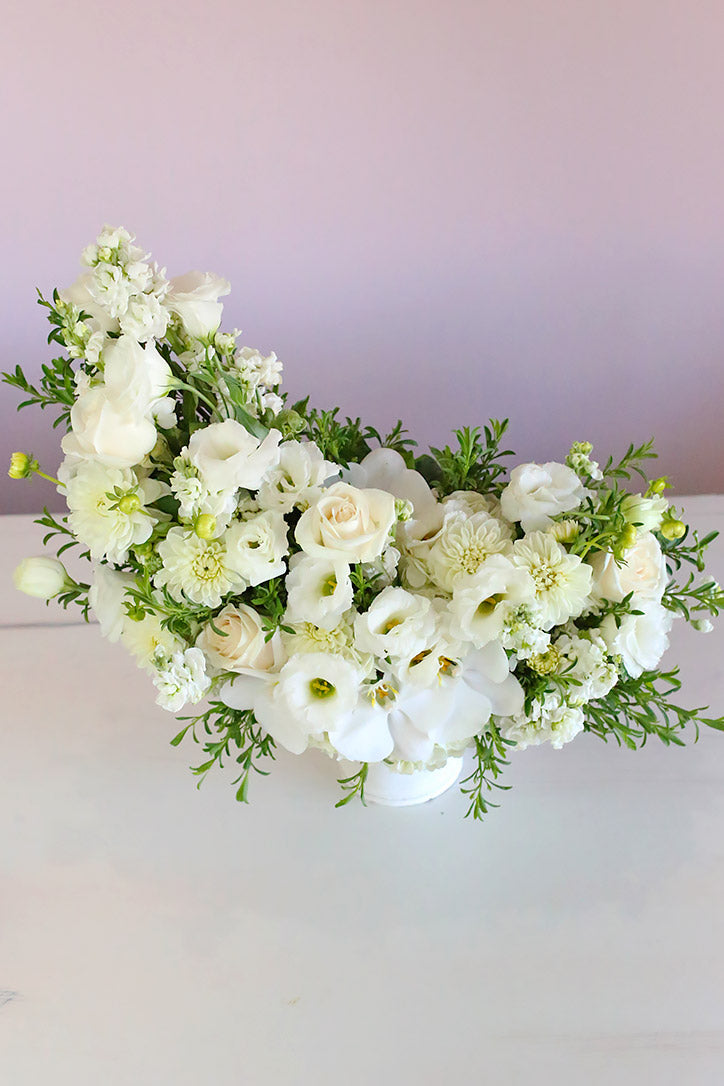 Overhead view of all-white rose blooms with orchids, lisianthus, dahlias, and hydrangeas 