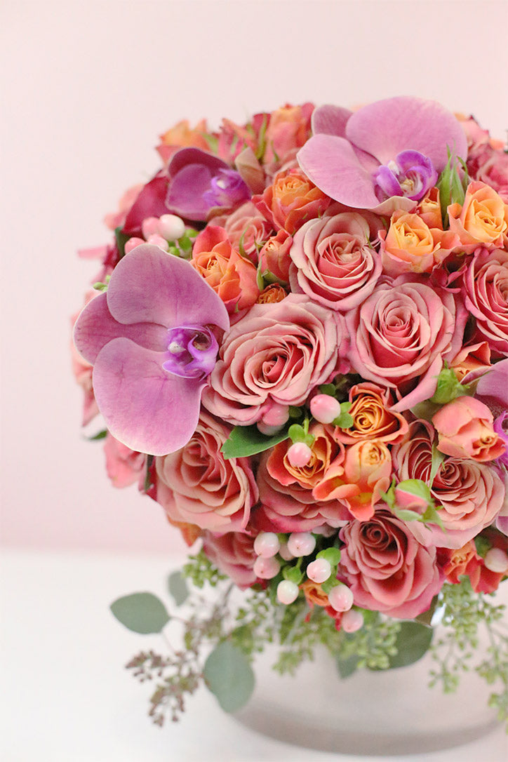 Side view of the coral-toned arrangement with coffee beans and seeded eucalyptus