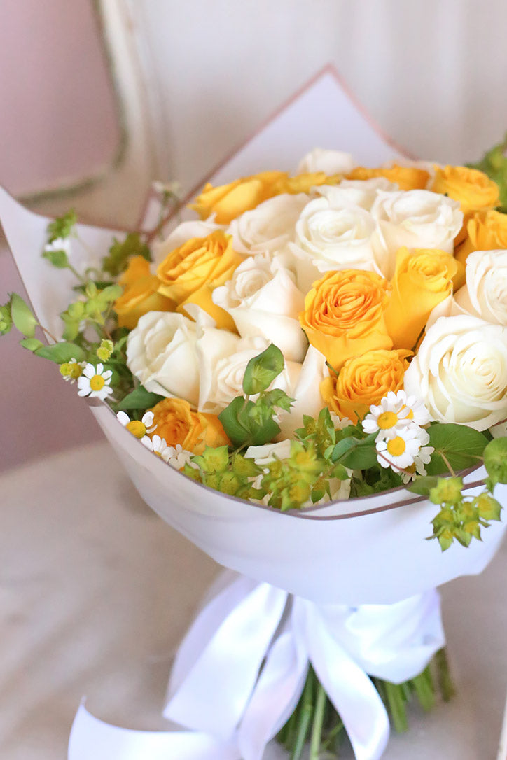 Bright yellow and white rose bouquet arranged in elegant wrap