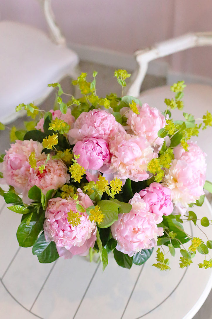 Pink peonies with voluminous blooms, lush pittosporum, and delicate gardenia leaves
