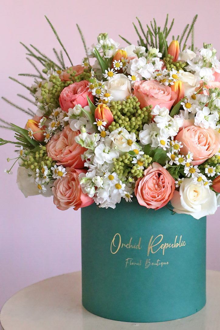 Close-up of orange tulips, salmon-pink garden roses, cream roses and white daisies