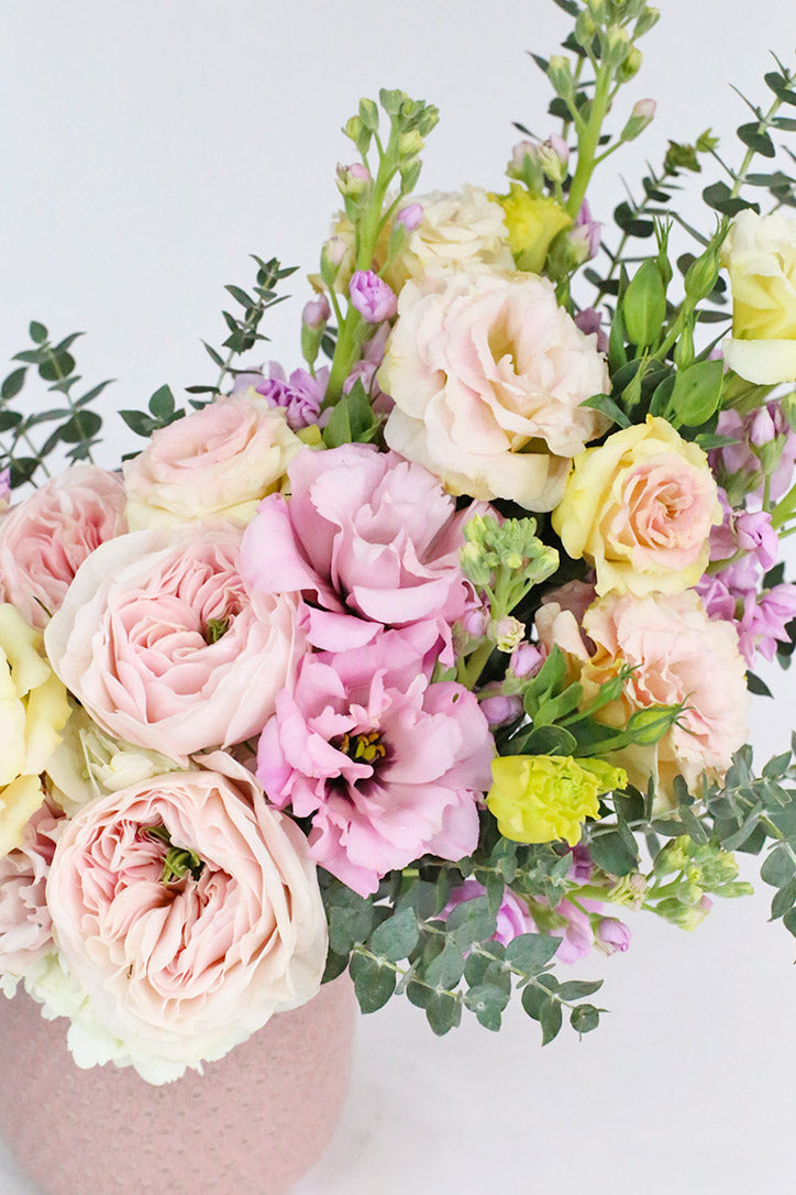 Side view of the soft spring floral arrangement in an elegant pink ceramic vase
