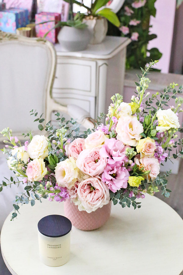 Pastel garden roses, spray roses, lisianthus and stock in a pink ceramic vase