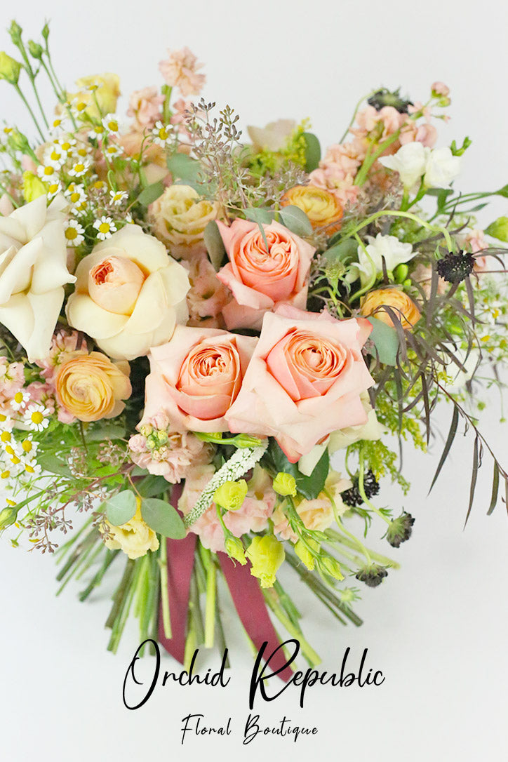 Close-up of blush roses, yellow ranunculus, black scabiosa and white veronica