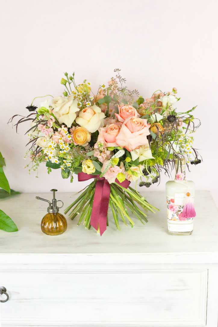 Blush and champagne rose bouquet with yellow ranunculus and chamomile tied with decorative ribbon 