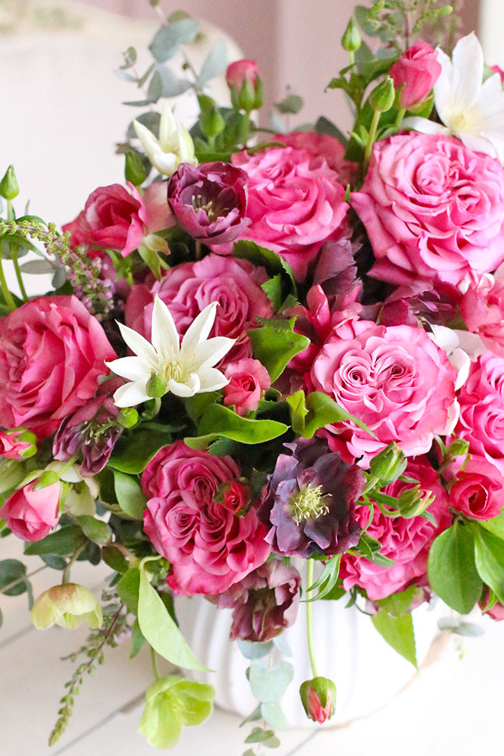 Close-up of vivid pink country roses, butterfly ranunculus and white clematis