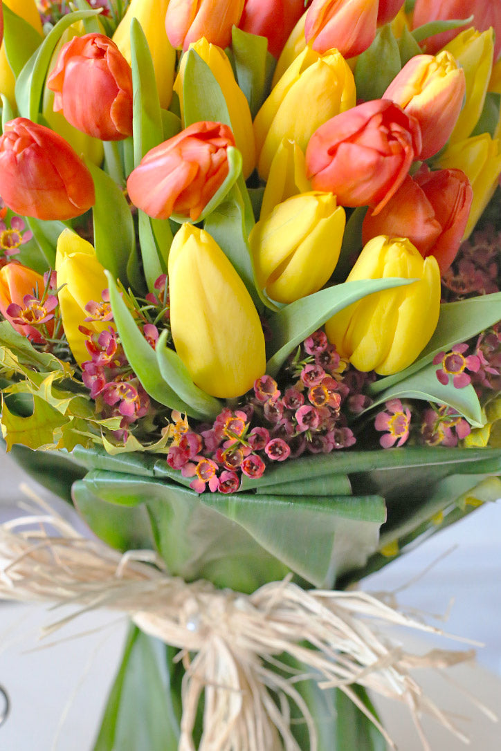 Tulip hand bouquet wrapped in emerald green specialty paper and secured with twine