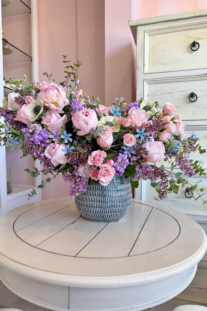 Pink peonies, O'Hara roses, white anemones and purple stock in a slate blue vase