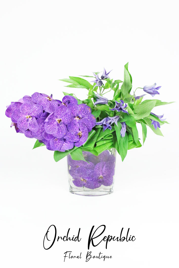 Purple Vanda orchids and clematis arranged in a sculptural luxury floral design