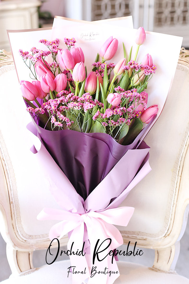 Cotton candy pink tulip and statice hand bouquet in fine paper wrapping
