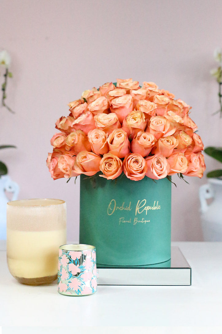Peach Country Home roses arranged in an olive green hat box with gold logo