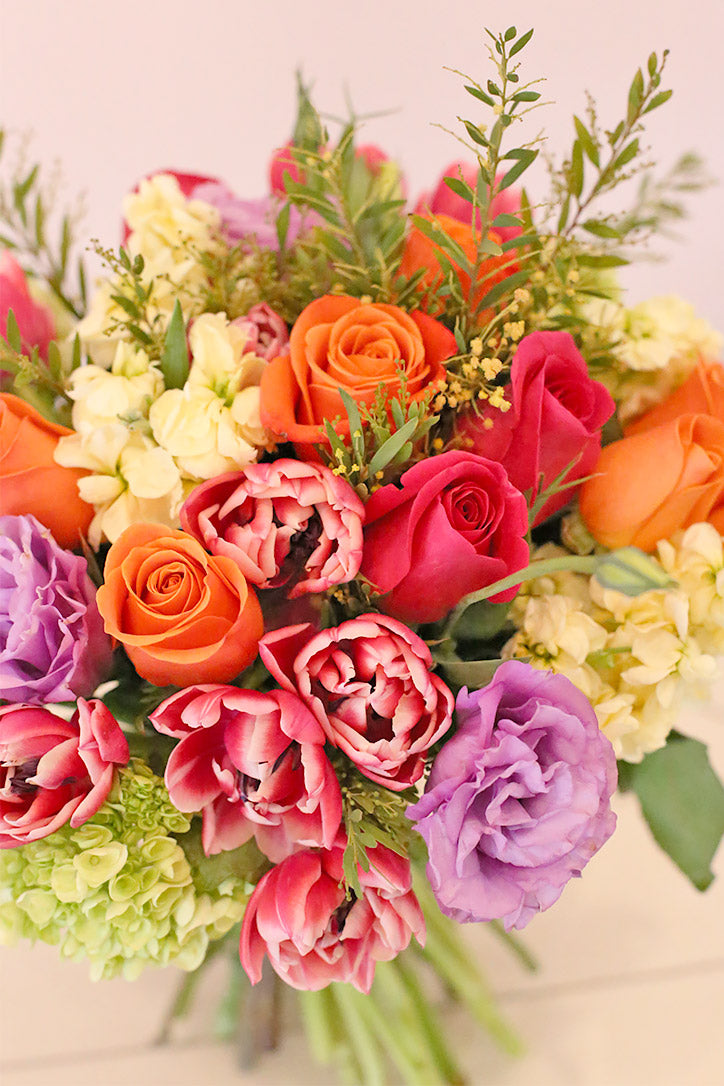 Close-up of vibrant tulips, roses, lisianthus and hydrangeas in sunset hues