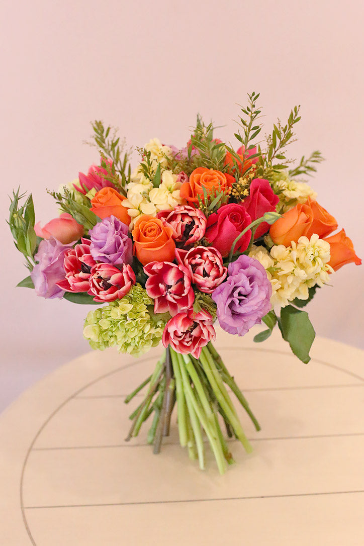 Sunset-colored tulip, rose and lilac bouquet secured with twine