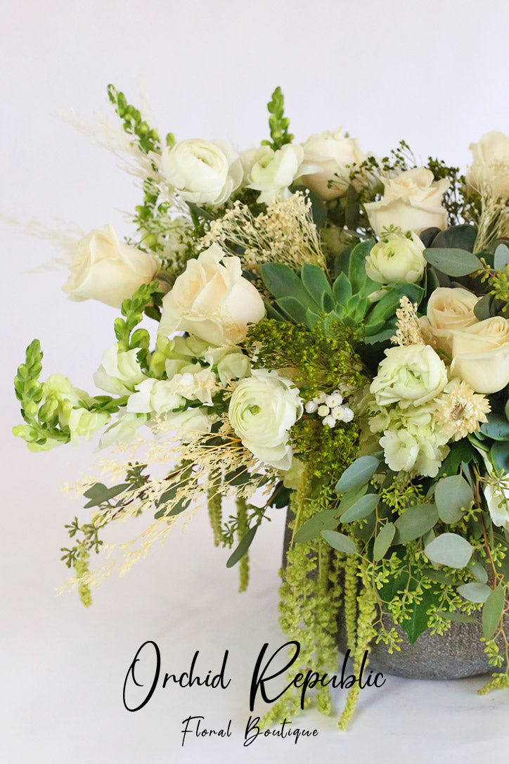 Side view of the white floral design with trailing amaranthus and seeded eucalyptus