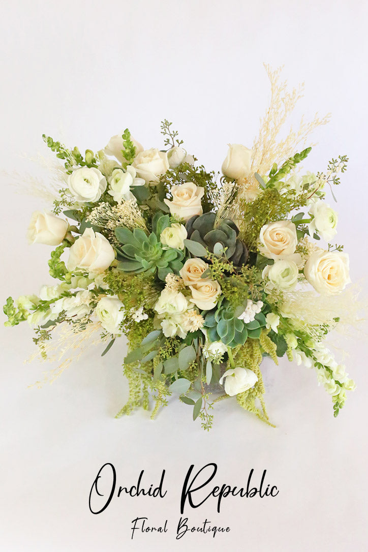 Close-up of creamy roses, white ranunculus, snapdragons and green succulents
