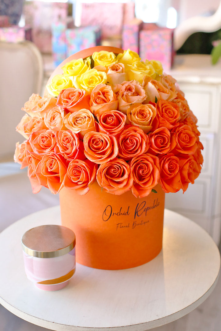 Gradient orange, peach and yellow rose arrangement in a luxury hat box
