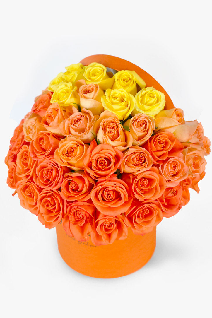 Ombre orange, peach, and yellow roses in a matching warm hatbox