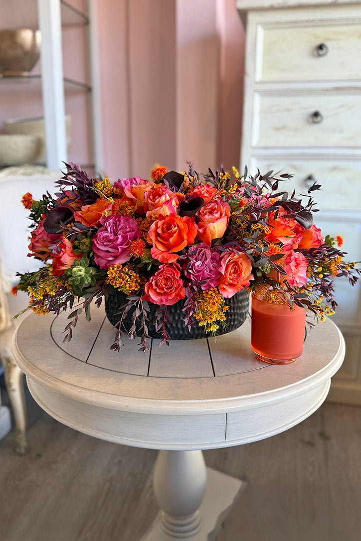 Orange and mauve country blue rose centerpiece with black calla lilies in a chic embossed oval pot