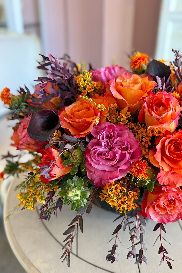 Close-up of orange Free Spirit roses, mauve Country Blue roses, black calla lilies, golden wax flowers, and sunflowers