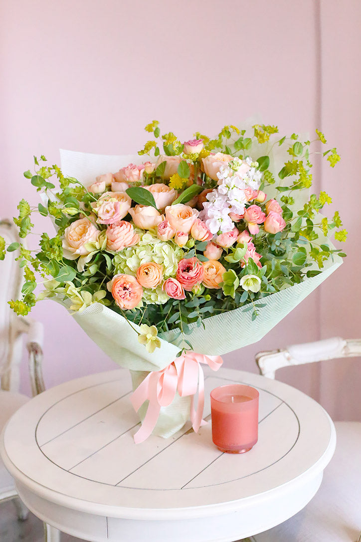 Juliet garden rose hand-tied bouquet with blush stock and peach ranunculus wrapped in fine paper 