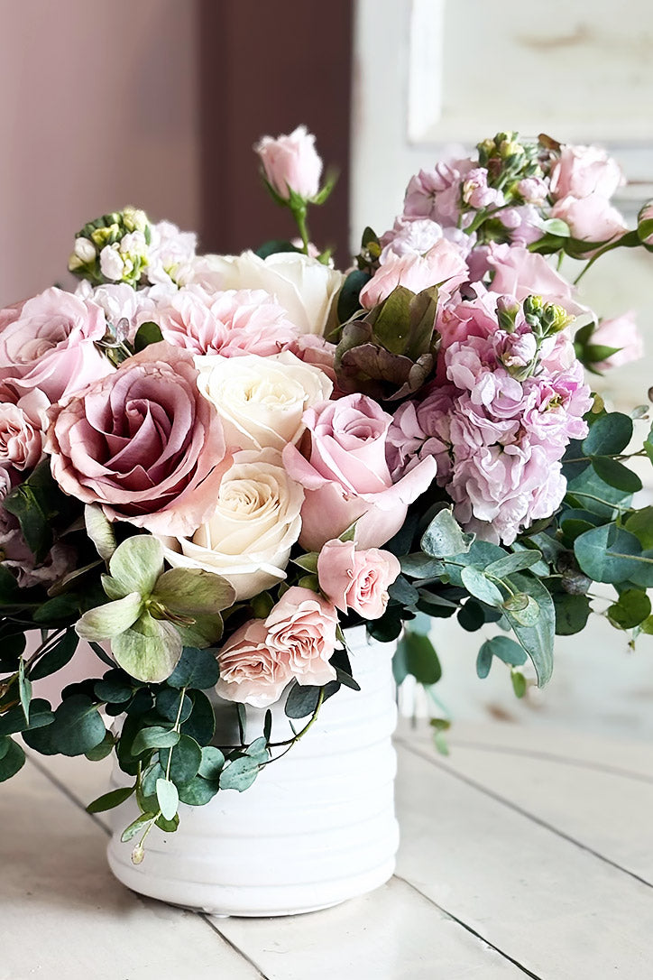 Side view of baby pink dahlias, dusty pink spray roses, cream roses and eucalyptus blooms