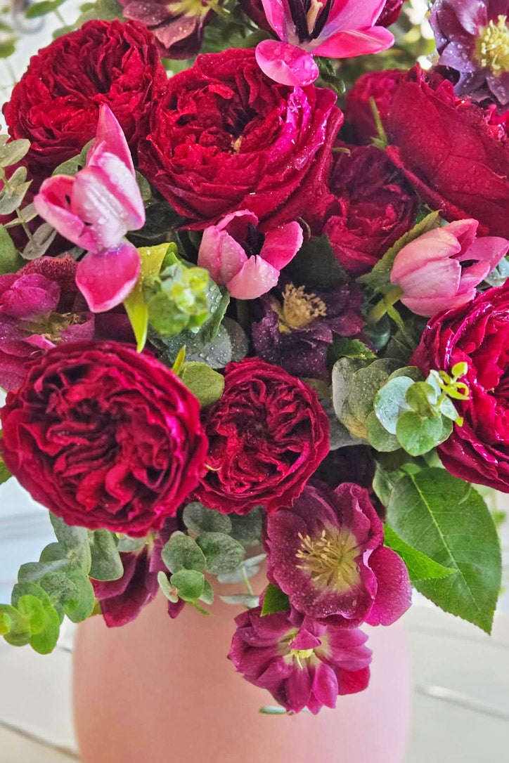 Close-up of burgundy garden roses, pink tulips, purple hellebores and baby eucalyptus