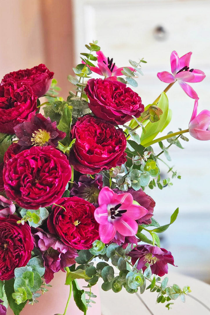 Close-up of burgundy garden roses, pink tulips, purple hellebores and baby eucalyptus