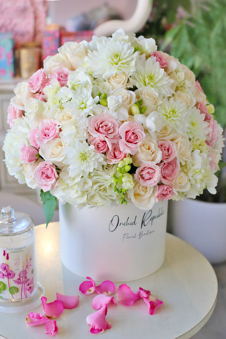 White hydrangeas and dahlias with peach and blush roses in a white hat box