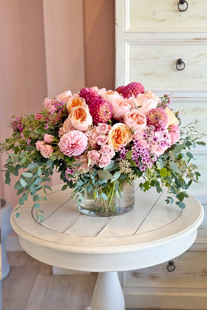 Pink dahlias and garden roses with hydrangeas in a clear glass vase