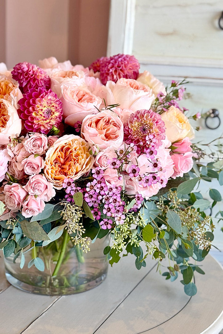 Side view of pink dahlias, roses, hydrangeas, and waxflowers with delicate foliage