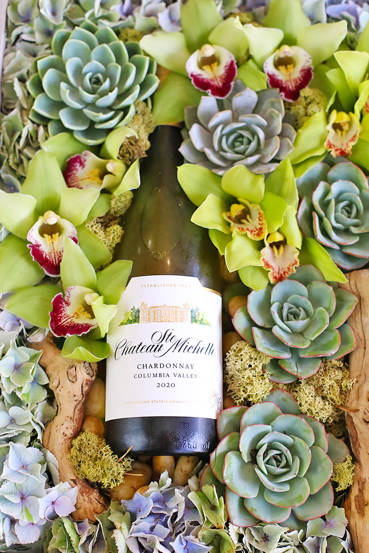 Close-up of green cymbidium blooms, rosette succulents, blue hydrangea and reindeer moss.