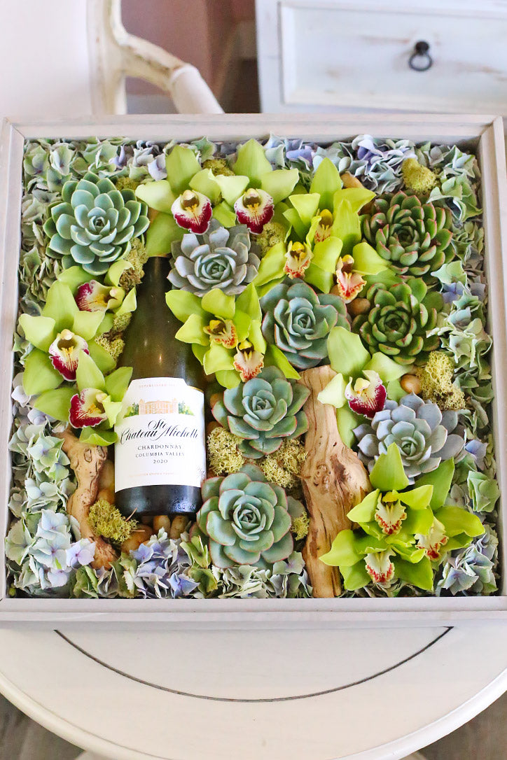 Wine gift box with green cymbidium orchids, succulents, blue hydrangea, moss and sculptural wood.