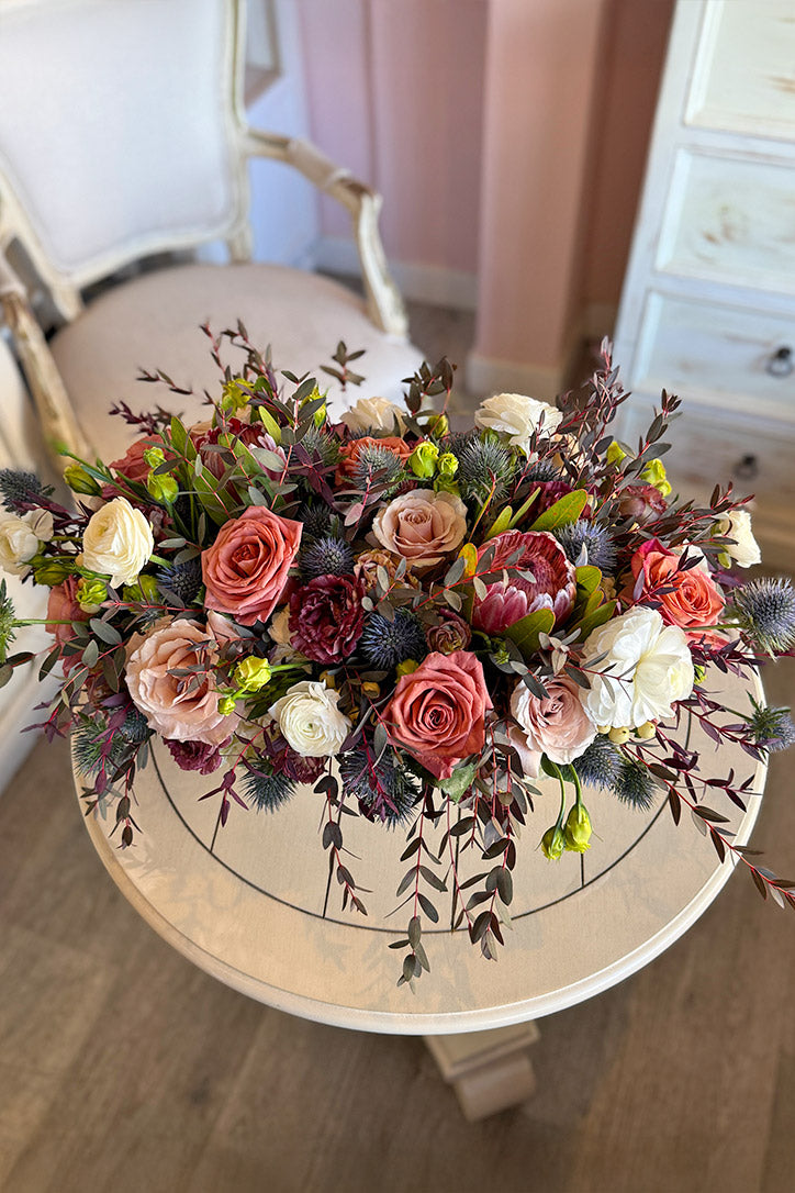 Full muted blush centerpiece with agonis, blue thistle and layered seasonal flowers